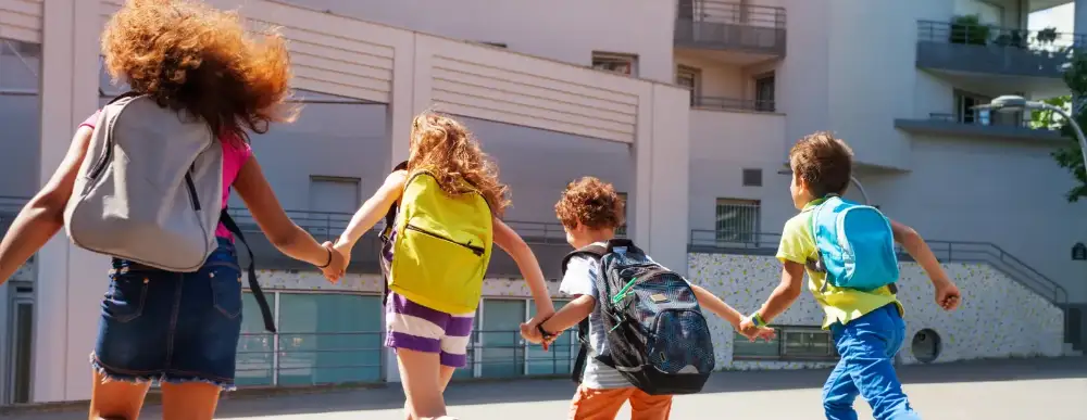 Four children heading to school backpacks