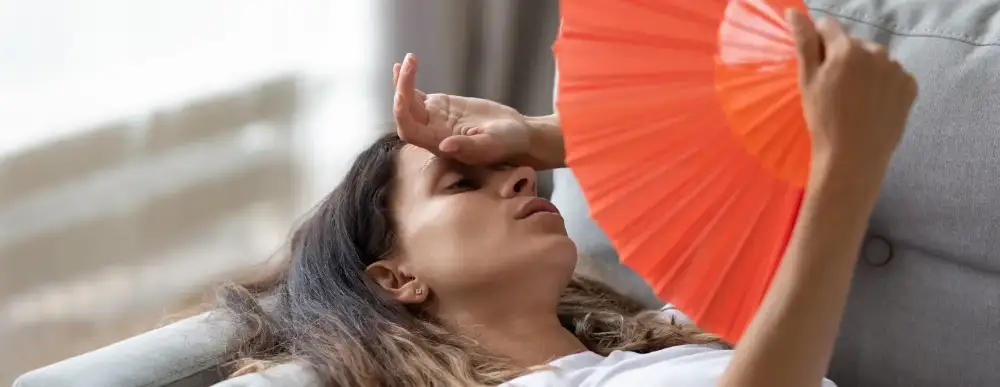 Woman at home, laying down, fanning herself