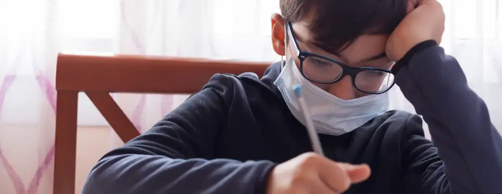 Boy doing homework with a mask