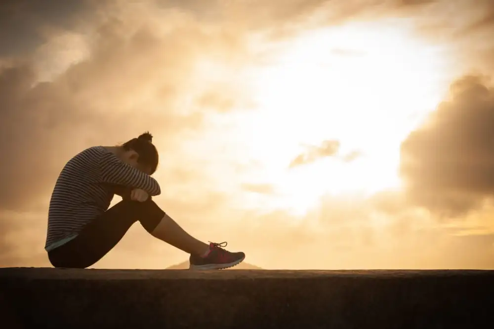 Woman sitting down with her head on her knees