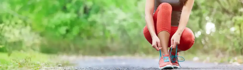 Woman kneeling to tie her shoe