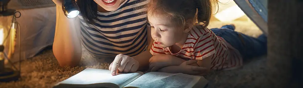 Mother and child reading by flashlight
