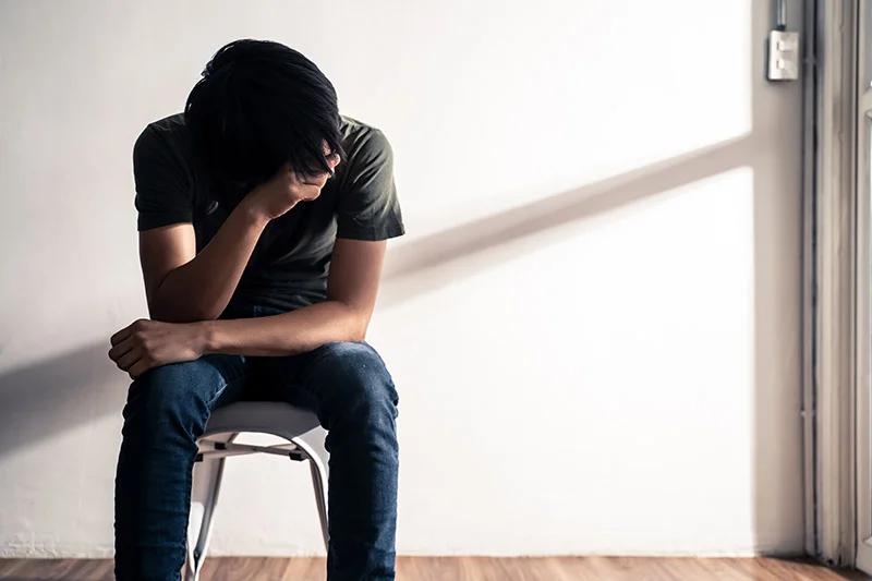 Person sitting in chair with head down