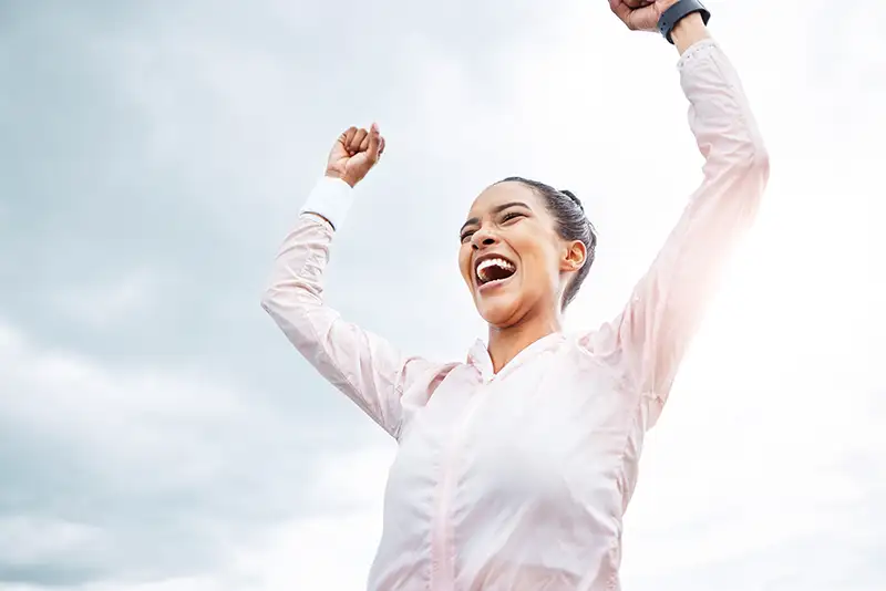 Healthy, looking woman, raising her hands in a victory pose