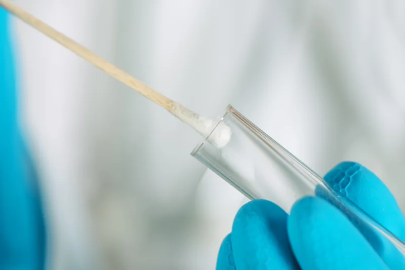 fingers putting swab in tube